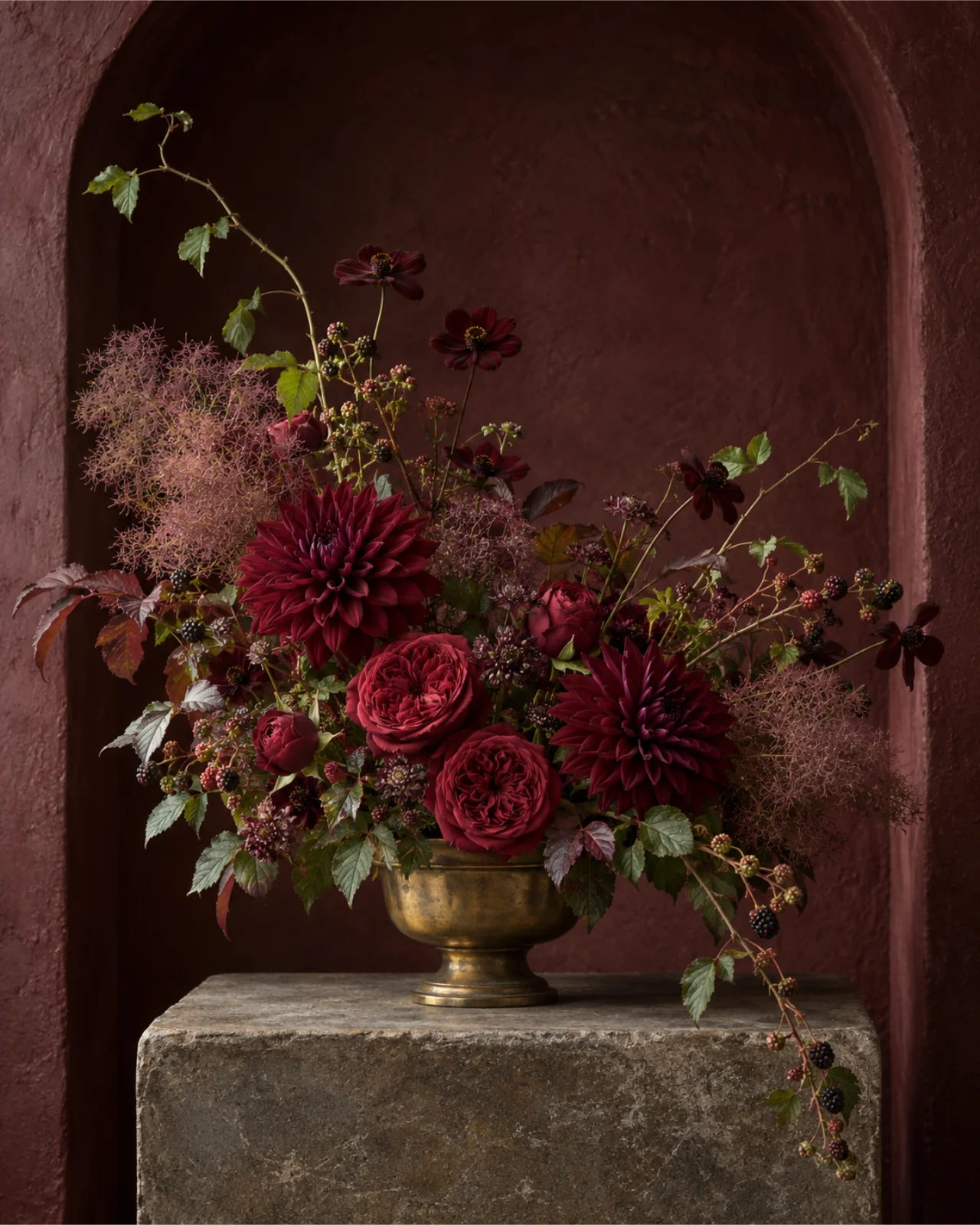 Burgundy dahlias and garden roses in an aged brass vessel